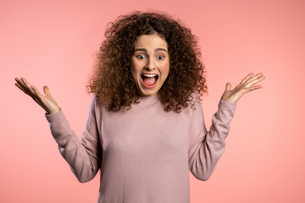 Close up of young scared curly girl shouting isolated over pink background. Stressed and depressed woman. Close up of young scared curly girl shouting isolated over pink background. Stressed and depressed woman.