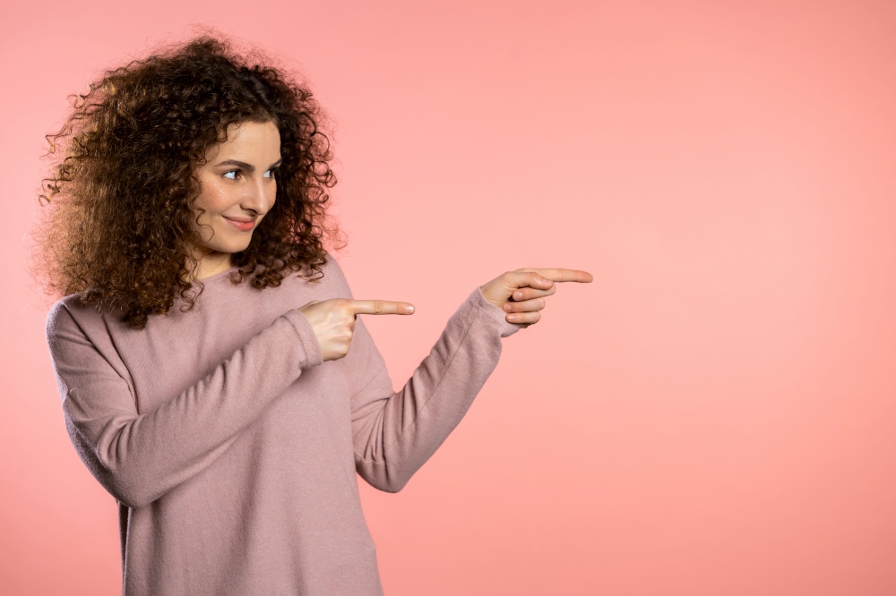Portrait of cute girl, she indicates with arms on her left with copy space. Happy smiling woman presenting and showing something isolated on pink background. Portrait of cute girl, she pointing with arms on her left with copy space. Happy smiling woman presenting and showing something isolated on pink background.