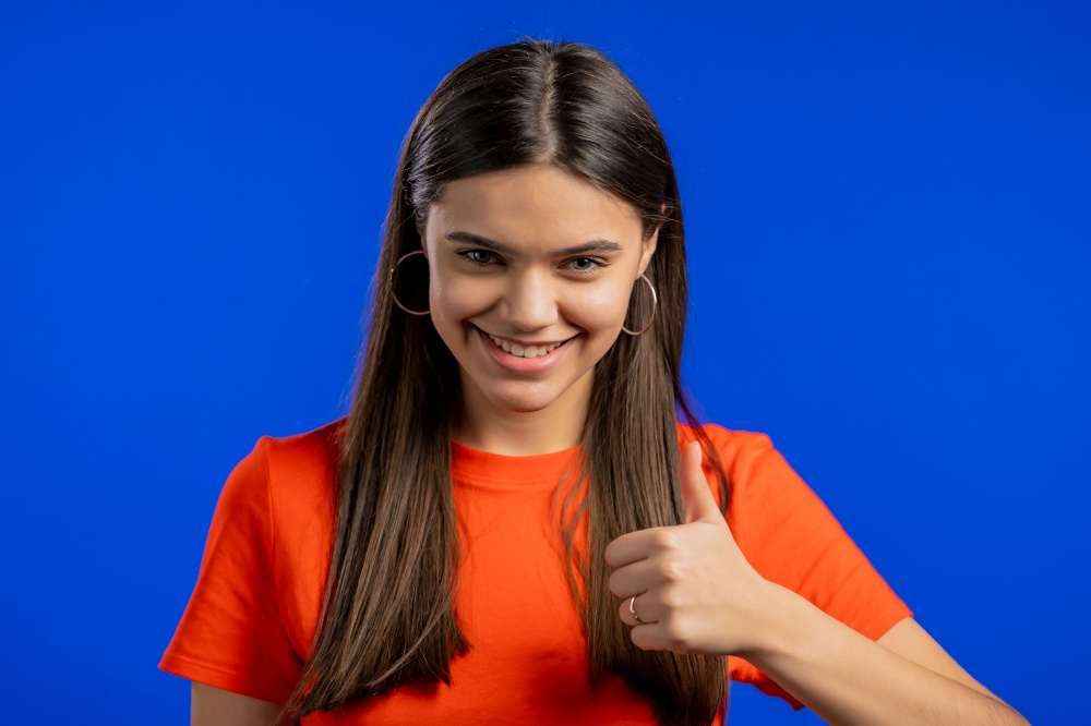 Woman showing Ok sign over studio background. Positive young girl smiles to camera. Winner. Success. Body language. Woman showing Ok sign over studio background. Positive young girl smiles to camera. Winner. Success. Body language.