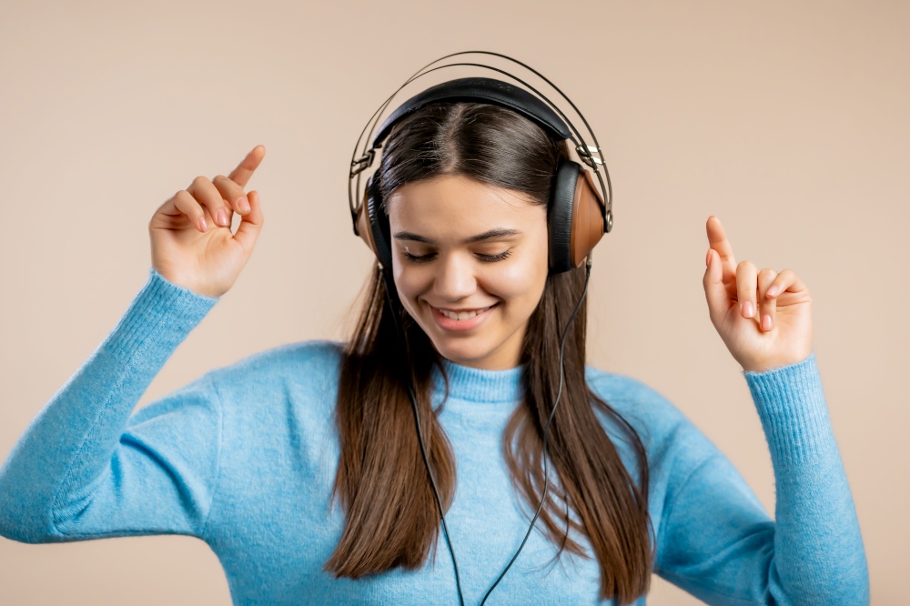 Cute woman dancing with headphones on light studio background. Cute girls portrait. Music, radio, happiness, freedom, youth concept. Cute woman dancing with headphones on light studio background. Cute girls portrait. Music, radio, happiness, freedom, youth concept.
