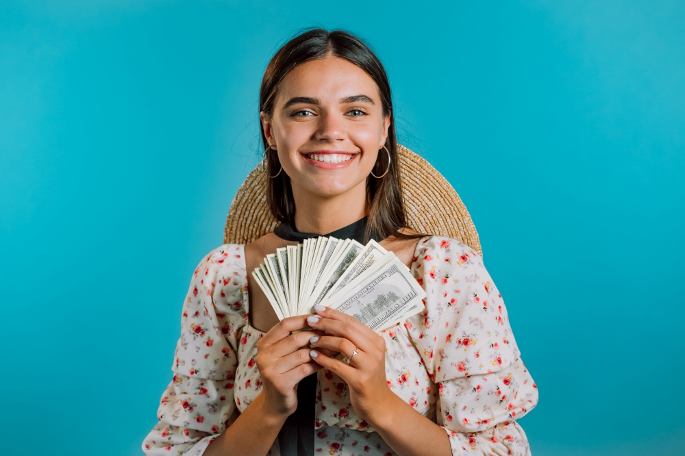 Amazed happy excited woman with money - U.S. currency dollars banknotes on blue wall. Symbol of success, gain, victory. Amazed happy excited woman with money - U.S. currency dollars banknotes on blue wall. Symbol of success, gain, victory.