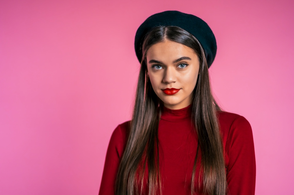 Beautiful cheerful european woman in red wear and french hat smiling to camera over pink wall background. Cute trendy girl&rsquo;s portrait. Beautiful cheerful european woman in red wear and french hat smiling to camera over pink wall background. Cute trendy girl&rsquo;s portrait.