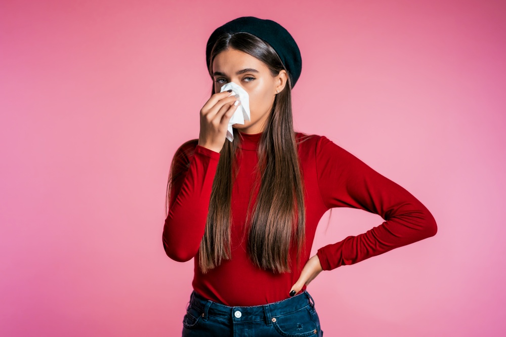 Young girl with long hair sneezes into tissue. Isolated woman is sick, has a cold or has allergic reaction. Health, medicine, illness, treatment concept. Young girl with long hair sneezes into tissue. Isolated woman is sick,has a cold