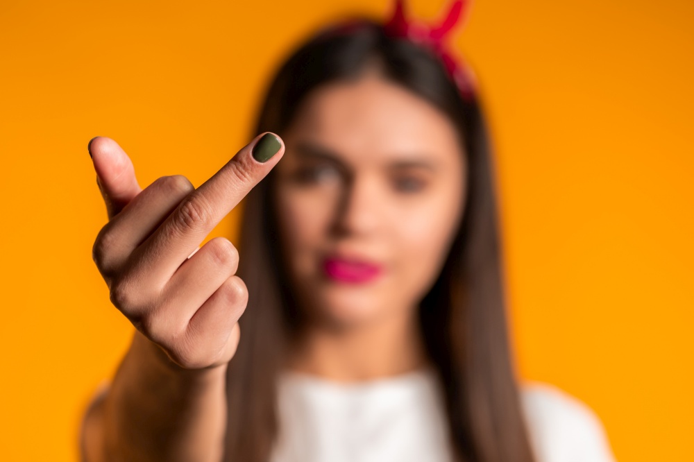 Young pretty woman on yellow background showing middle finger - gesture of fuck. Expression negative, aggression, provocation. Young pretty woman on yellow background showing middle finger - gesture of fuck. Expression negative, aggression, provocation.