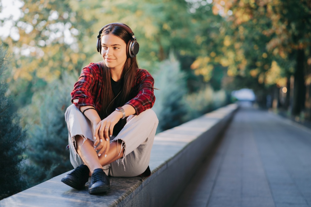 Portrait of attractive girl dancing with earphones in park. Woman smiling. moves to the rhythm.Friendly appearance of modern trendy hipster.. Portrait of attractive girl dancing with earphones in park. Woman smiling. moves to the rhythm.Friendly appearance of modern trendy hipster