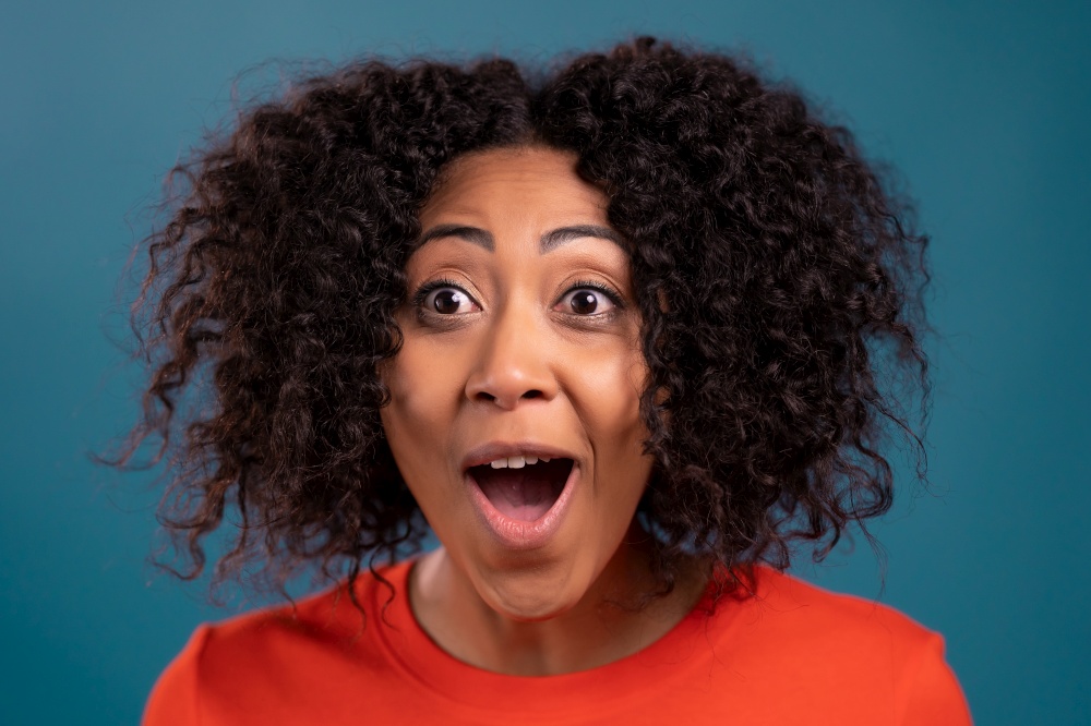 African woman is very glad, she screaming WOW loud. Concept of sales, profitable offer. Excited happy lady on blue studio background. High quality photo. African woman is very glad, she screaming WOW loud. Concept of sales, profitable offer. Excited happy lady on blue studio background.