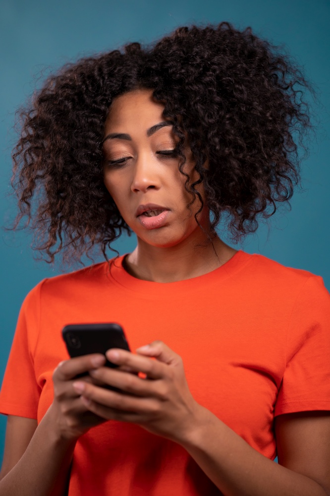 Attractive african woman using mobile phone on blue background. Technology, success, victory, happiness concept. High quality photo. Attractive african woman using mobile phone on blue background. Technology, success, victory, happiness concept.