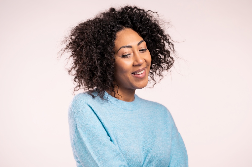 Modest african woman in blue basic sweater on white studio background. Girl looks aside, shy. . High quality photo. Modest african woman in blue basic sweater on white studio background. Girl looks aside, shy.