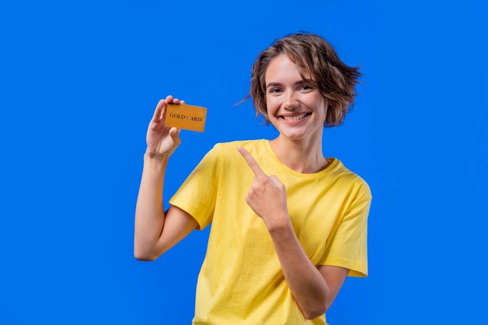 Successful pretty woman showing unlimited gold credit card and look to camera blue studio background. High quality photo. Successful pretty woman showing unlimited gold credit card and look to camera blue studio background.