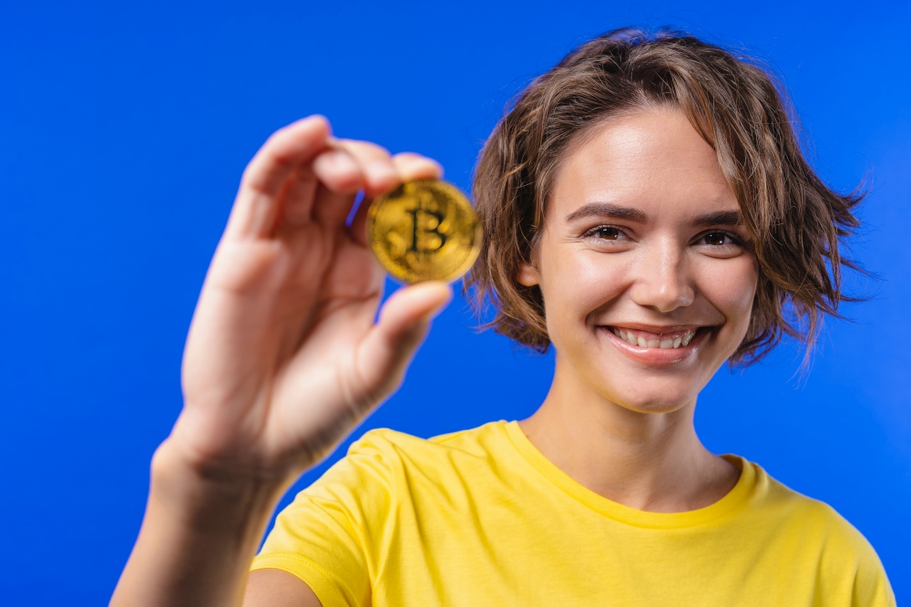 Woman with bitcoin, crypto currency. Golden coin on blue background. Digital exchange, popularity of BTC, symbol of future money, electronics industry, mining concept. High quality photo. Woman with bitcoin, crypto currency. Golden coin on blue background. Digital exchange, popularity of BTC, symbol of future money, electronics industry, mining concept.