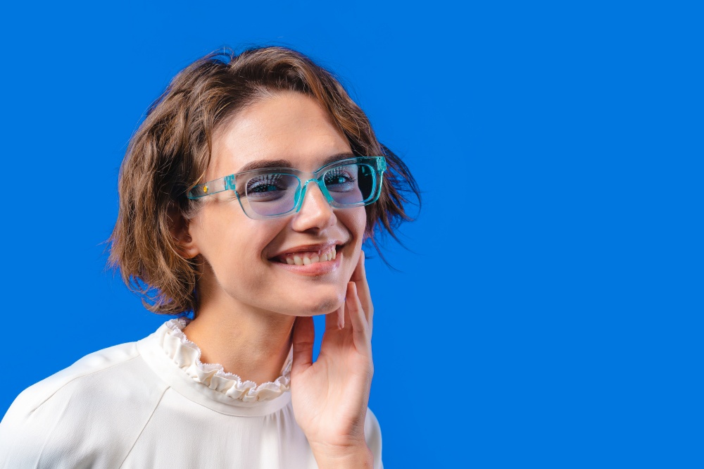 Smiling woman in transparent blue glasses. Positive stylish lady. Eyewear, sunglasses, fashion accessories. Studio background, copy space. High quality photo. Smiling woman in transparent blue glasses. Positive stylish lady. Eyewear, sunglasses, fashion accessories. Studio background, copy space.