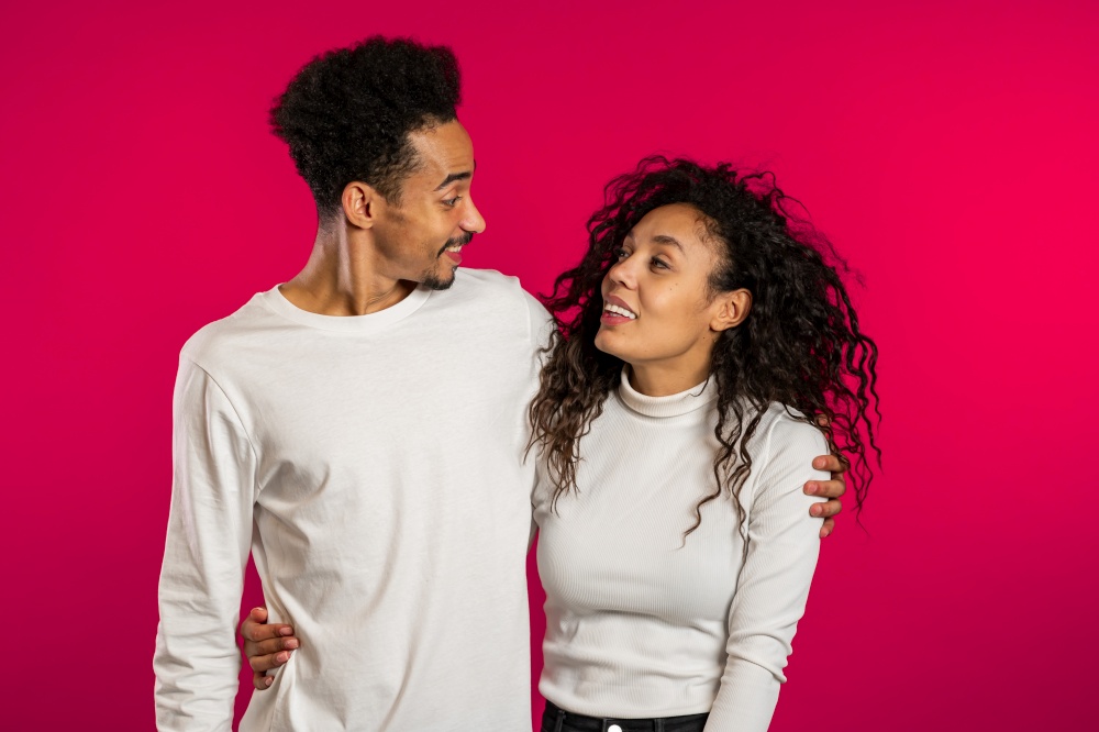 Portrait of young african american match on red studio background. Love, holidays, happiness concept. Portrait of young african american couple on red studio background. Love, holidays, happiness concept.