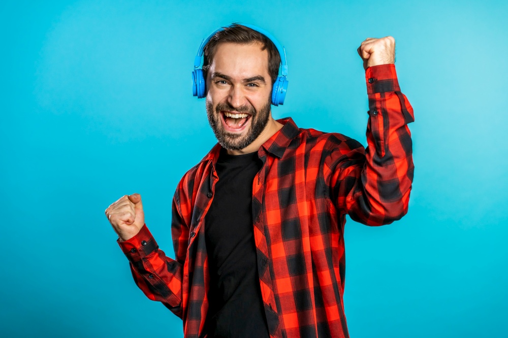Handsome man with headphones dancing isolated on blue background. Party, music, lifestyle, radio and disco concept. Handsome man with headphones dancing isolated on blue background. Party, music, lifestyle, radio and disco concept.