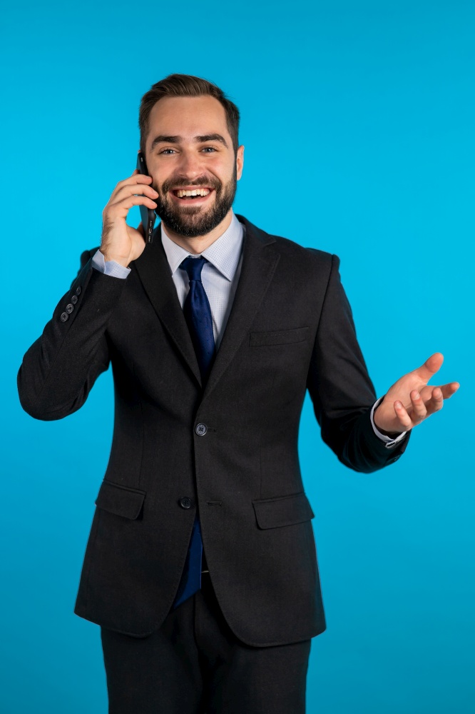 Businessman have conversation using mobile phone isolated on blue background. Business guy in formal suit gladly talks with colleague. Office employee, wage worker, weekdays concept.. Businessman have conversation using mobile phone isolated on blue background. Business guy in formal suit gladly talks with colleague. Office employee, wage worker, weekdays concept