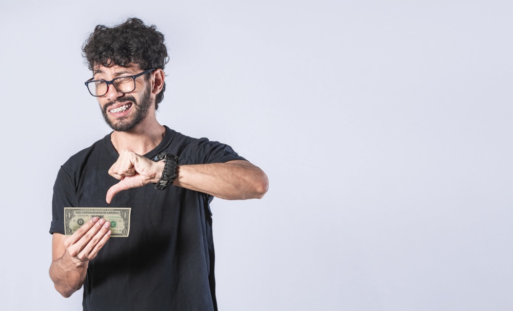 Sad man holding banknote, Sad man with a banknote with thumb down, concept of man with little money