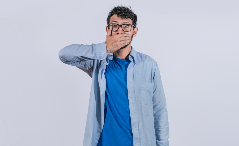Surprised man covering his mouth on isolated background, Surprised man in glasses covering his mouth, concept of astonished man covering his mouth