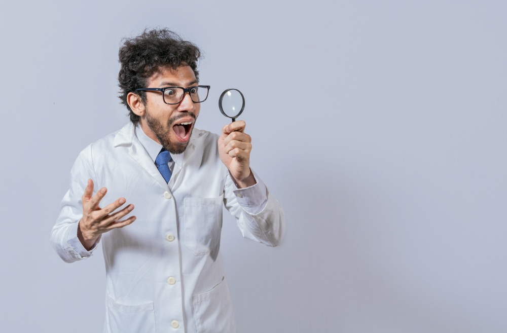 Surprised scientist observing with a magnifying glass to the side. Scientist holding a magnifying glass looking to the side, Man in a white coat with a magnifying glass looking advertisement