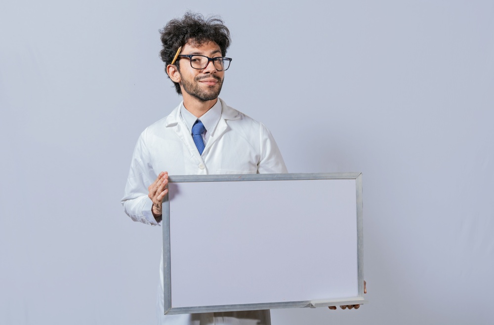 Professor in white coat holding small blank blackboard isolated. Scientist in glasses in a white coat is holding a blank whiteboard. Scientist showing blank whiteboard concept