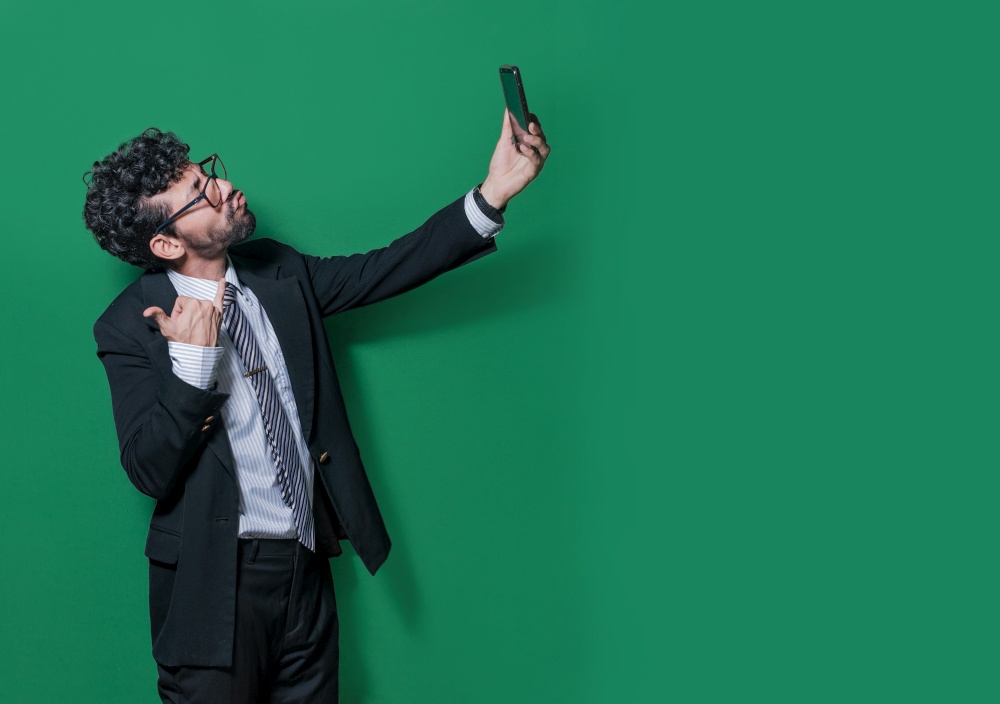 Young businessman taking a selfie with funny gestures, Businessman taking funny selfies isolated, Concept of businessman guy taking a selfie and blowing kisses on the cell phone