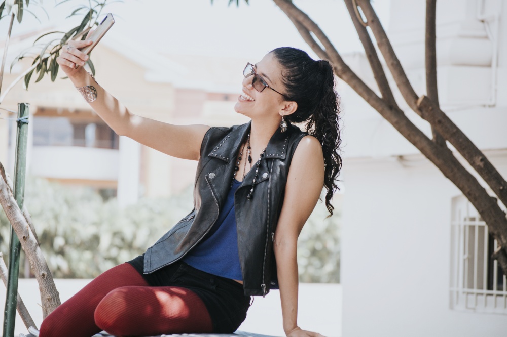 Close-up of a girl taking a selfie, urban girl taking a selfie outdoors, lifestyle woman smiling and taking a selfie