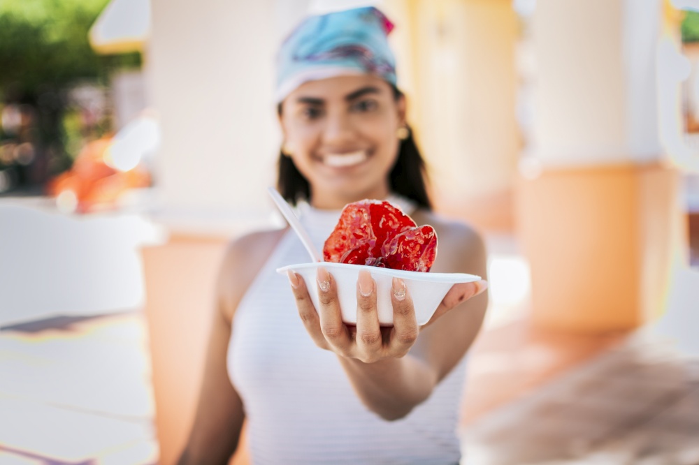 Close up of young woman holding a shaved ice in the street. Concept of a girl with a Nicaraguan raspado, Raspado of Nagarote. Smiling girl holding shaved ice on the street