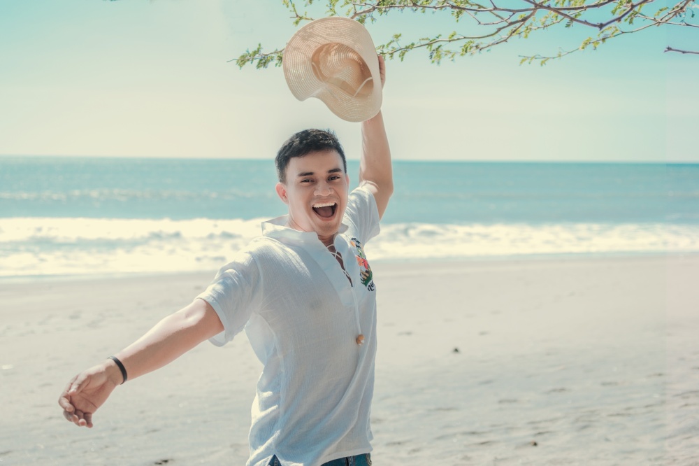 Happy handsome man on vacation outdoors, Happy latin young man on the beach, Tourist travel concept