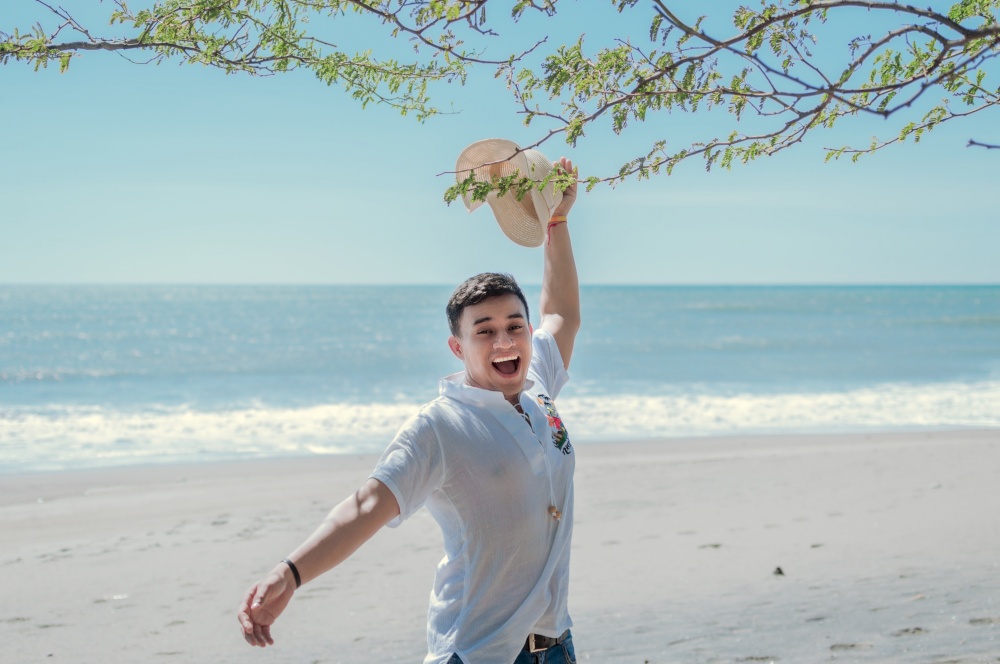 Happy handsome man on vacation outdoors, Happy latin young man on the beach, Tourist travel concept