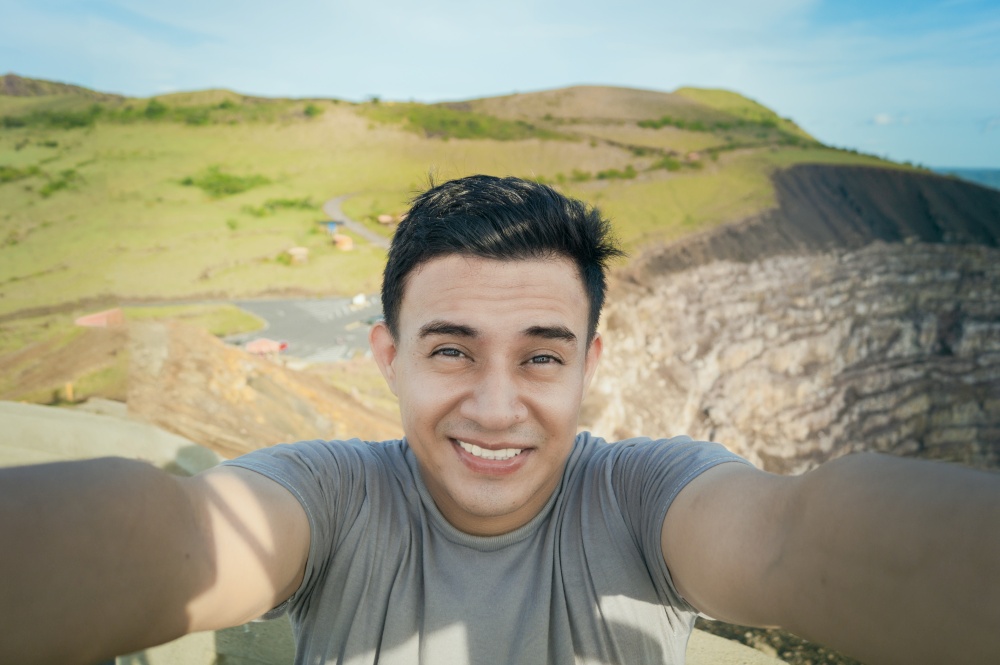 Adventurous man taking a selfie at a viewpoint. Close up of person taking an adventure selfie, Tourist taking a selfie at a viewpoint. Handsome tourist taking a selfie on vacation
