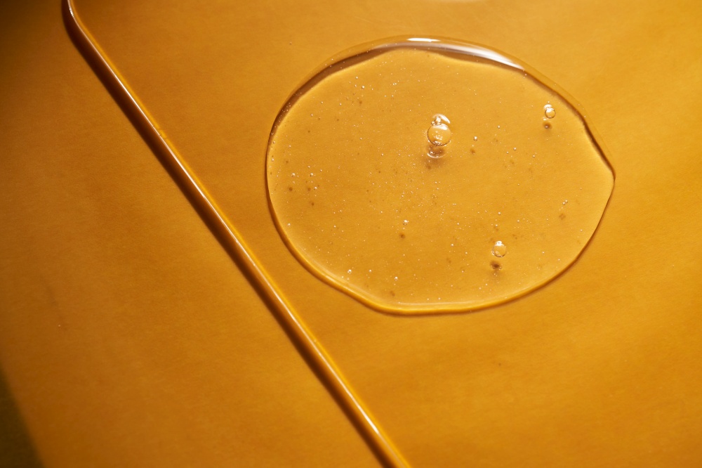 A drop of body gel or shampoo on a yellow saturated background. Texture.