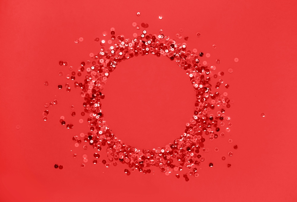 Sequins red confetti lined in a round frame red background. Abstract festive composition place for text. Valentine&rsquo;s Day holiday concept. Sequins red confetti lined round frame red background. Abstract festive composition place for text