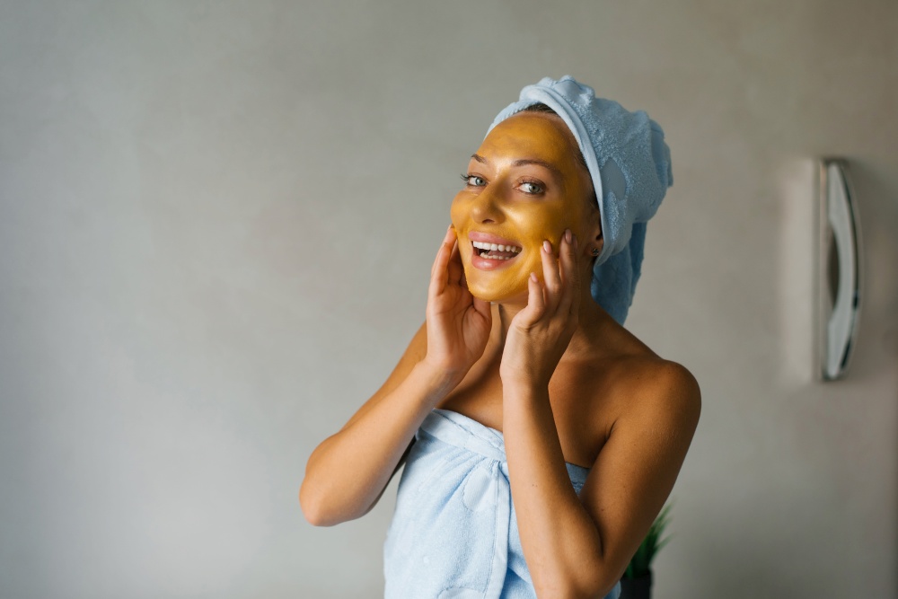 Smiling woman applies a face mask after a shower