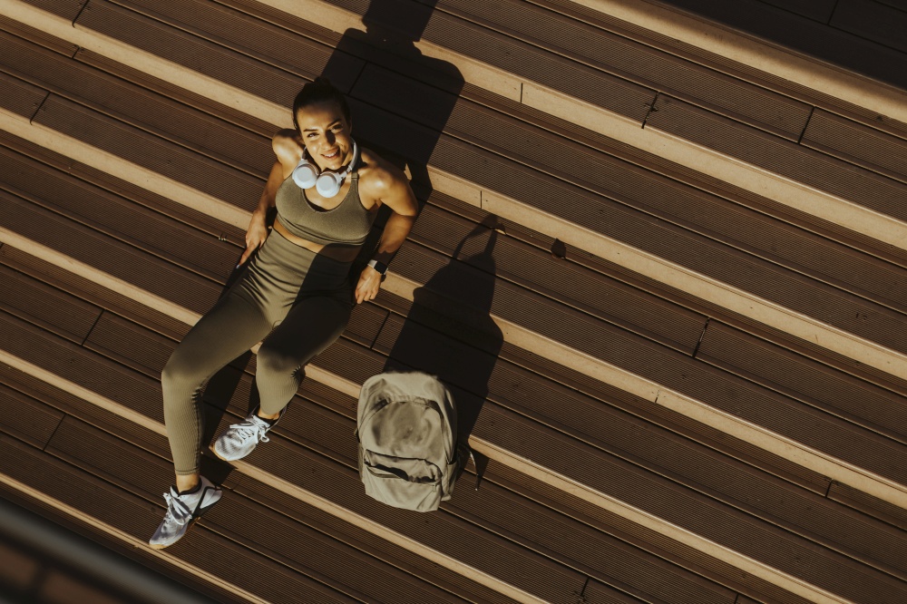 Over view at pretty young woman takes a break after running in the urban area