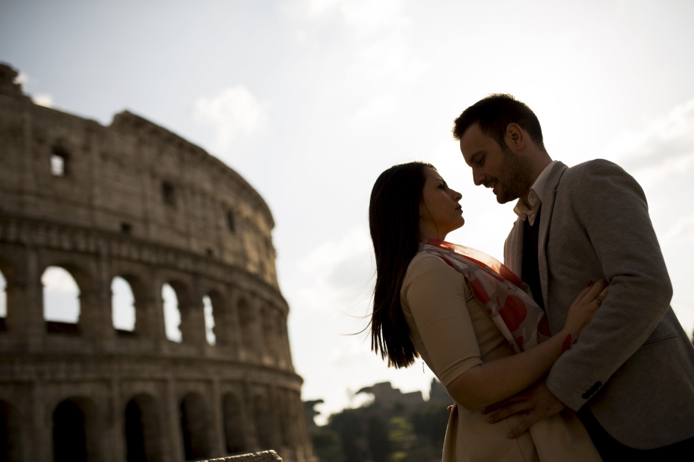 Young couple in love in front of the Colosseum in Rome at sunset
