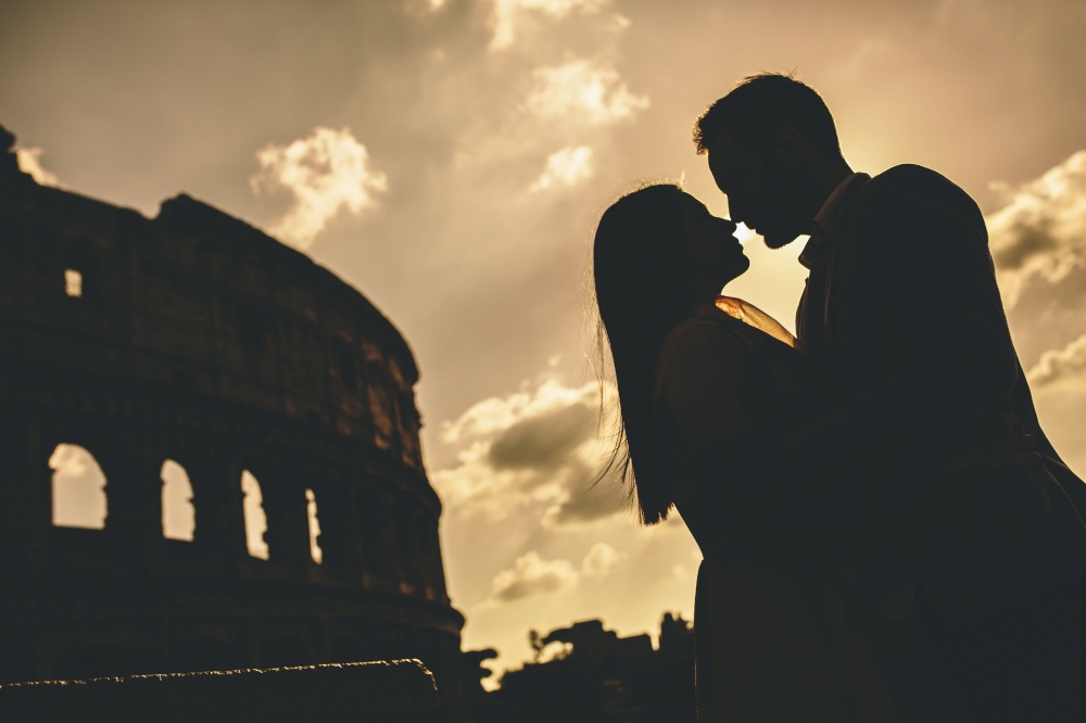 Young couple in love in front of the Colosseum in Rome at sunset