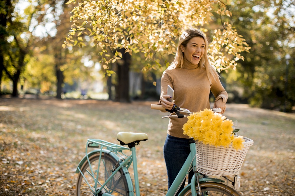 Happy active woman riding bicycle in golden autumn park