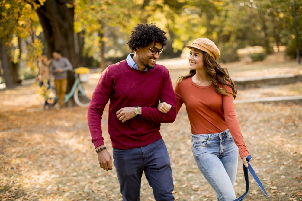 Loving beautiful couple African American man and Caucasian woman walking in the autumn park