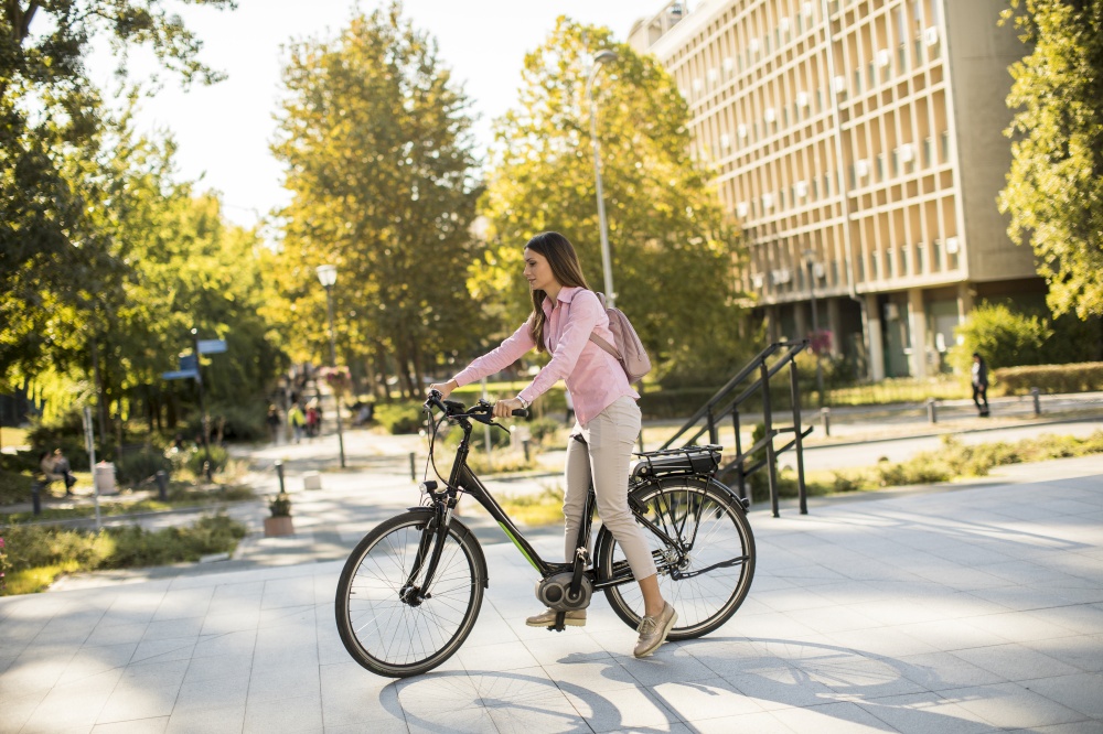 Young woman riding an electric bicycle in urban environment