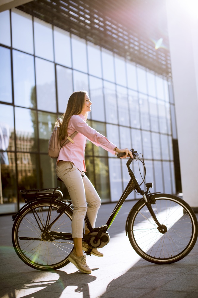 Young woman with tablet and e-bike outdoor on sunny day