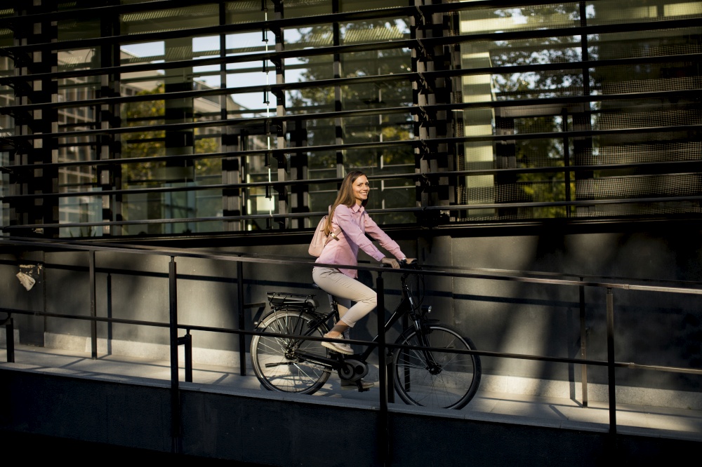 Young woman riding e bike in urban enviroment at sunny day