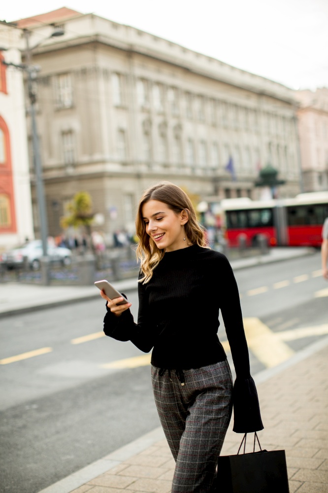 Young woman on the street with mobile phone and listening music