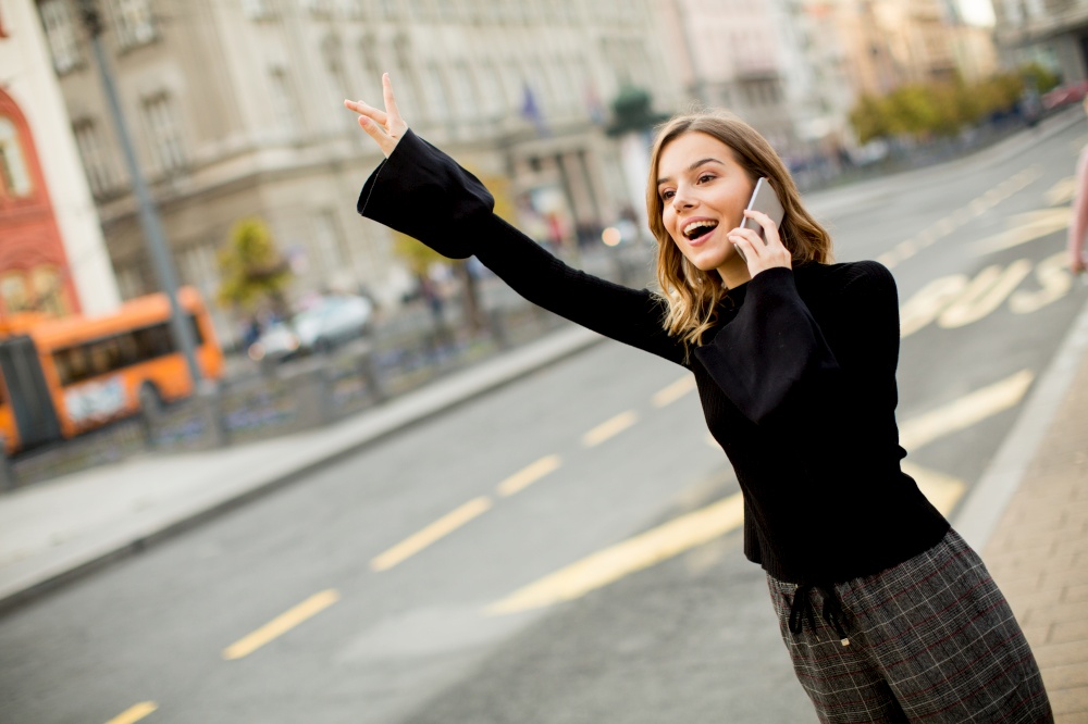 Young woman waiting for taxi or bus on the street in the city