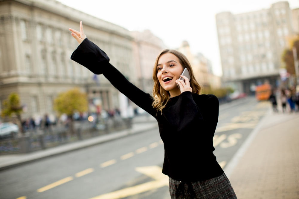 Young woman waiting for taxi or bus on the street in the city