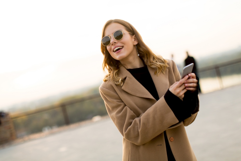 Portrait of young woman with eyeglasses with mobile phone outdoor