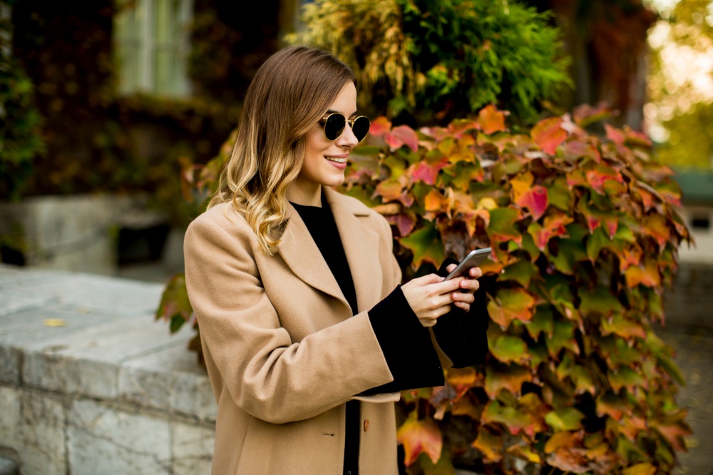 Portrait of young woman with mobile phone at autumn outdoor