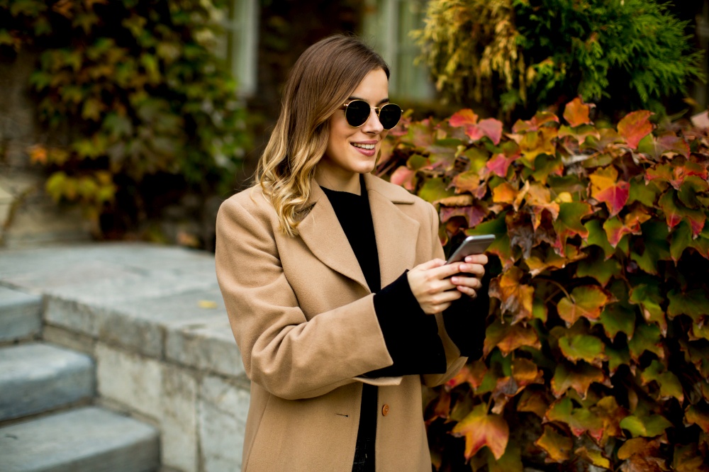 View at modern woman using mobile phone at autumn outdoor