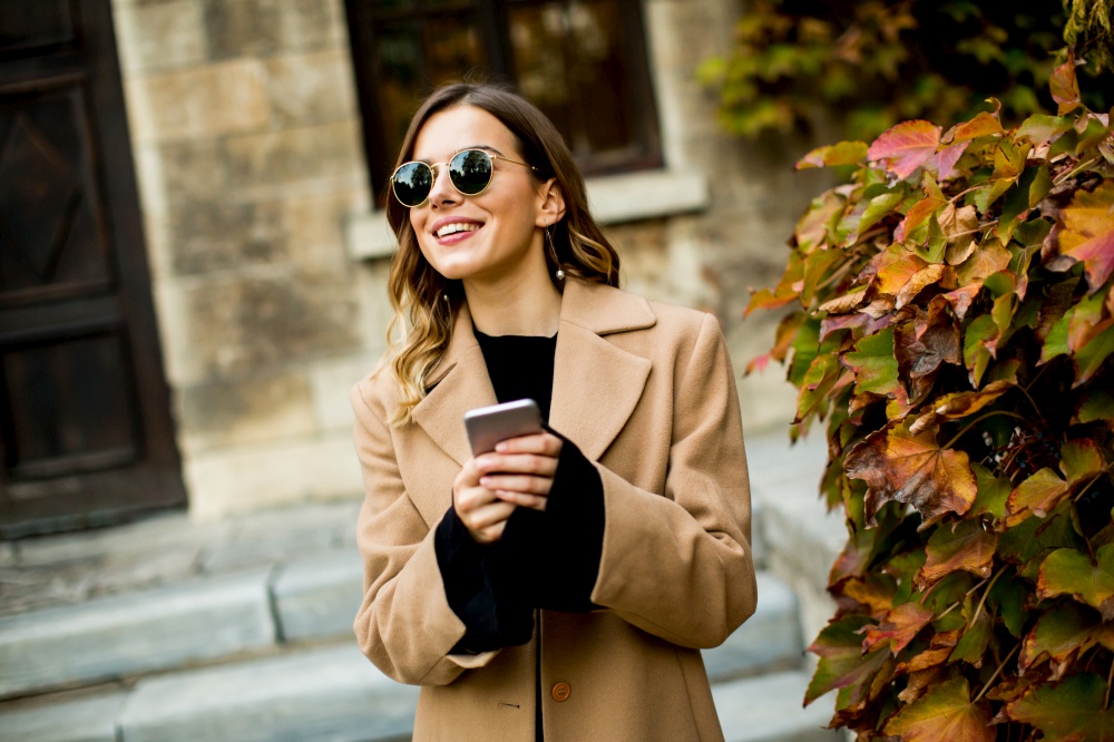 Portrait of young woman with mobile phone at autumn outdoor