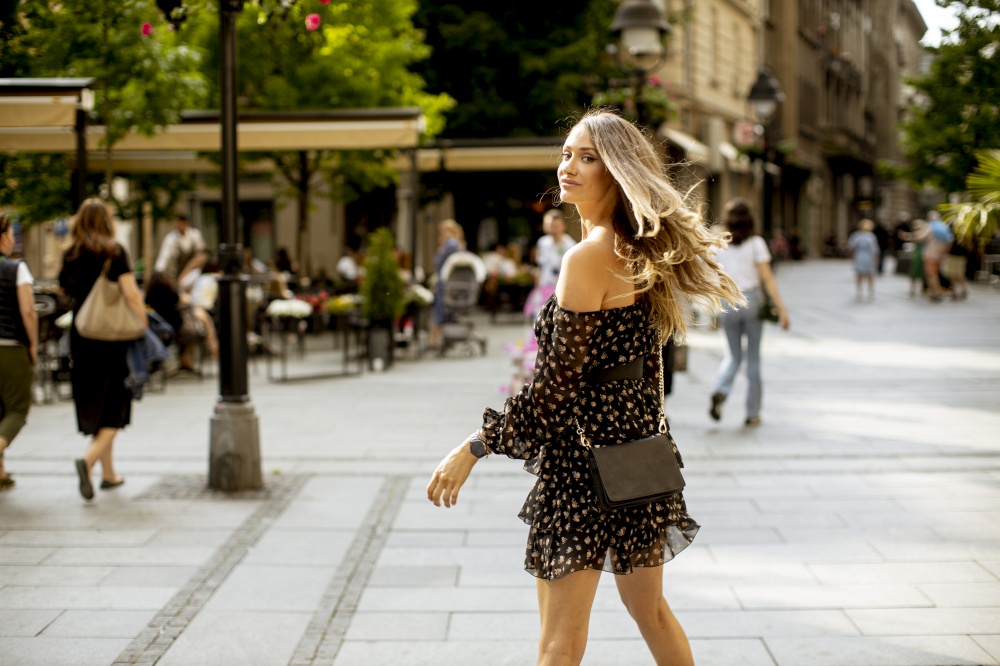 Pretty young long hair brunette woman walking on the city street