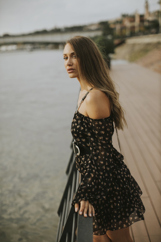 Pretty young long hair brunette woman standing on the riverside