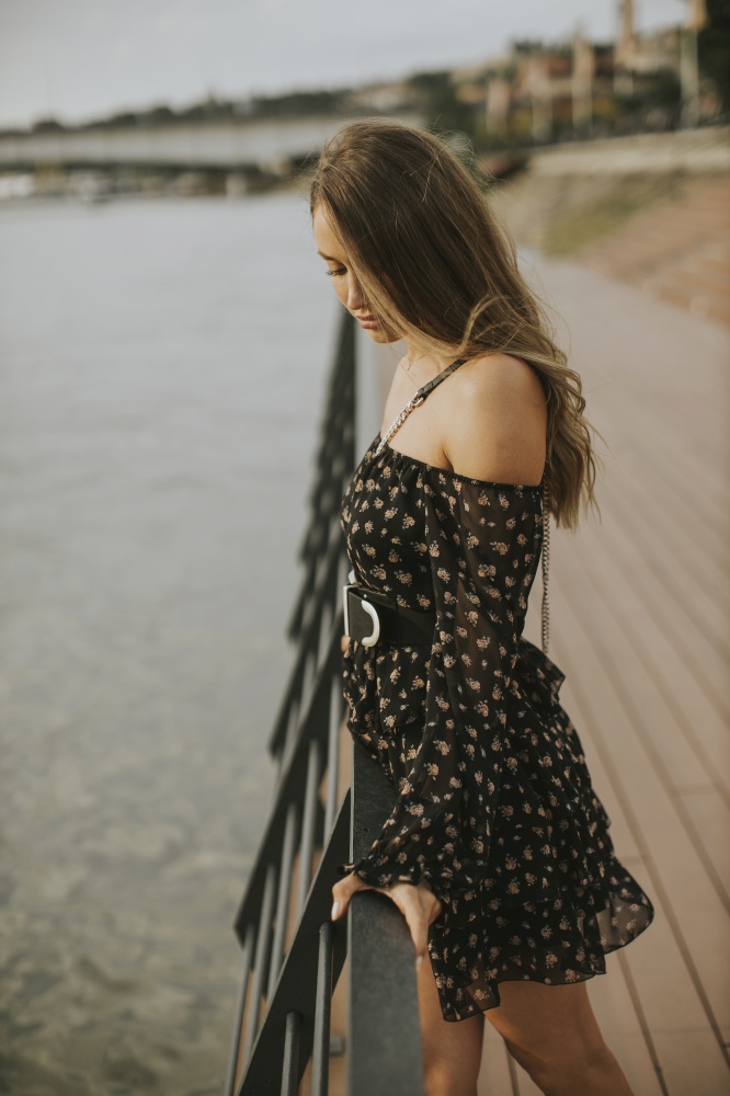 Pretty young long hair brunette woman standing on the riverside