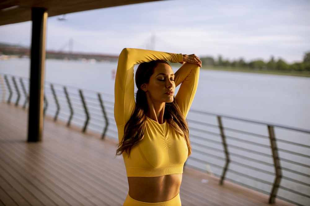 Beautiful young woman stretching on the riverside